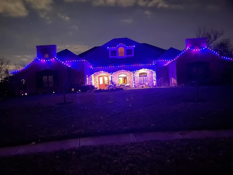 Home lit in purple and blue uplighting with a warm roofline run above it