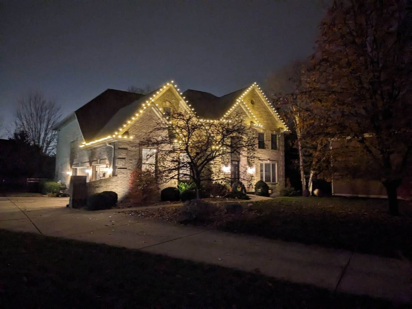 Warm white roofline and gables lit against the treeline on a Cincinnati home