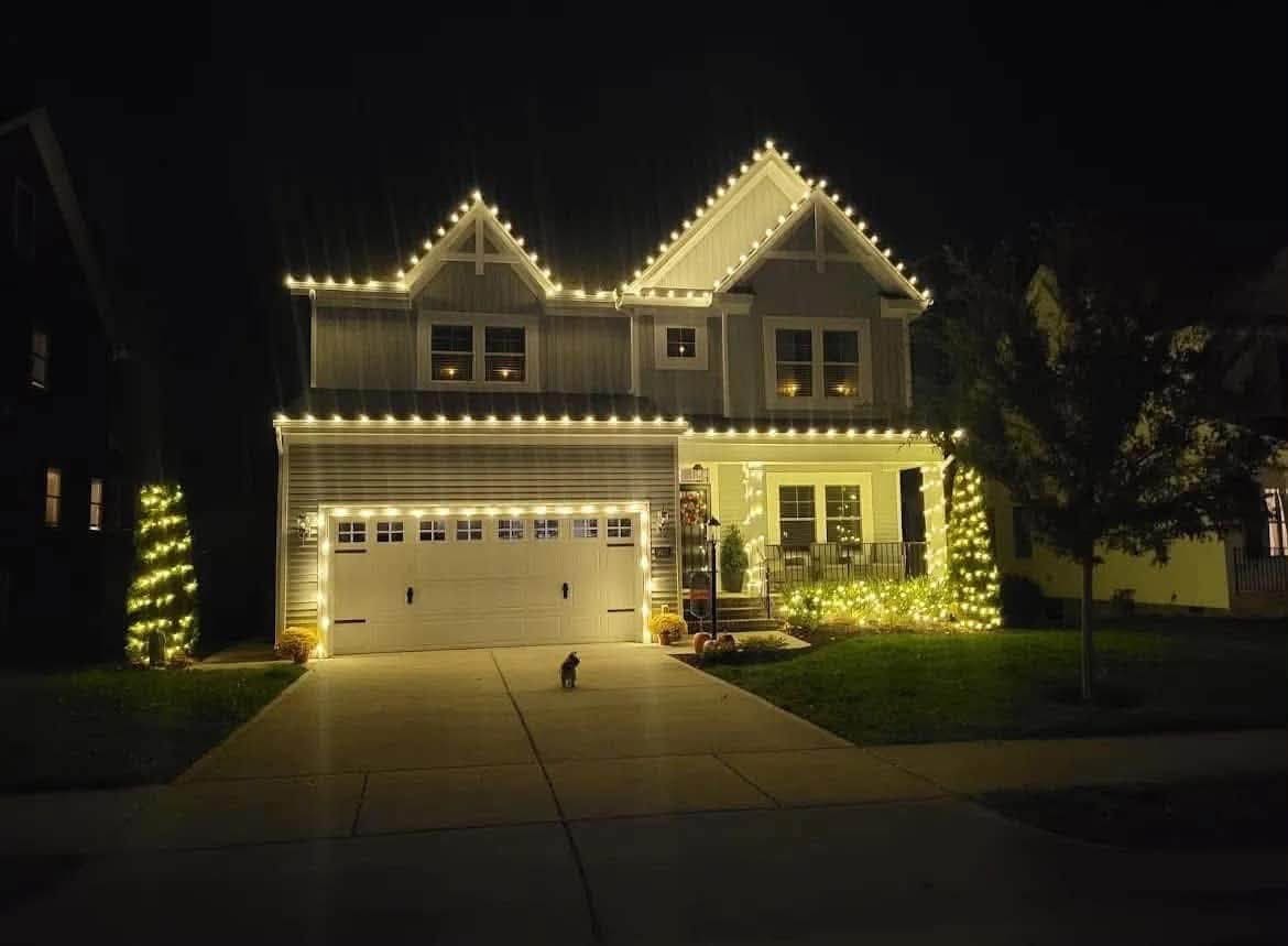 Two-storey home with warm white lights along every roofline and the garage gable